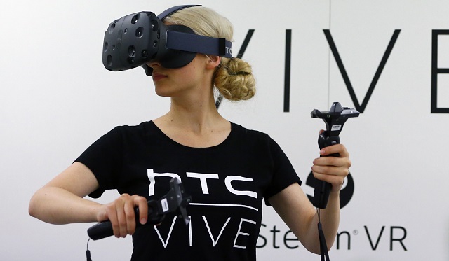 A woman checks a pair of Vive Virtual Reality goggles, produced by Taiwan's HTC, during the Gamescom 2015 fair in Cologne, Germany August 5, 2015. The Gamescom convention, Europe's largest video games trade fair, runs from August 5 to August 9. REUTERS/Kai Pfaffenbach - RTX1N5FQ
